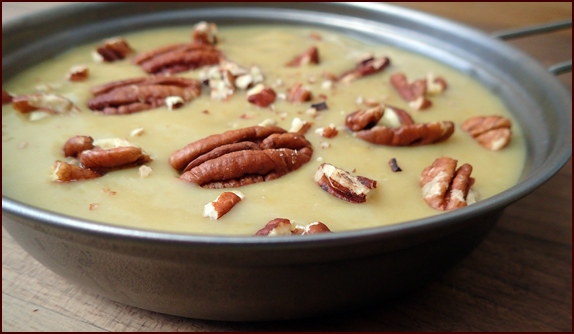 Photo shows one serving of Banana-Mango Fruit Pudding with Coconut Milk garnished with pecan pieces.