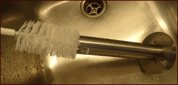Cleaning inside of pineapple corer with bottle brush.