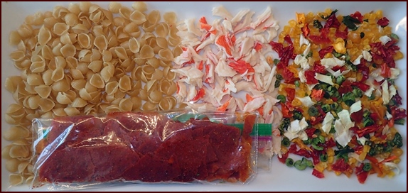 Dehydrated ingredients for Crab Marinara Soup. Pasta shells, imitation crab, mixed vegetables, tomato sauce leather.
