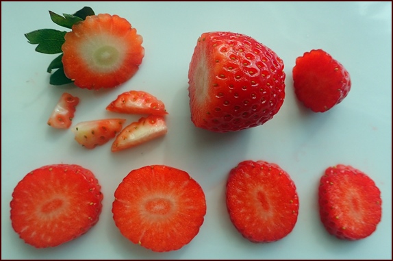 Cutting strawberries for dehydrating. Set aside tops and bottoms for making strawberry fruit leather.