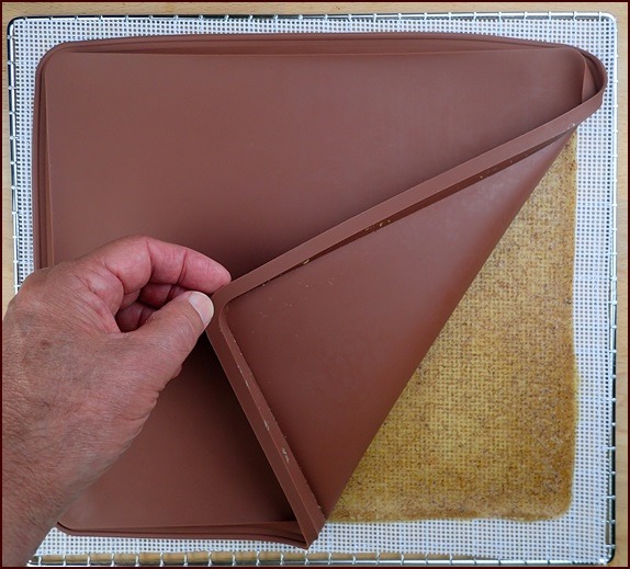 Peach-kiwi fruit leather flipped onto a silicone mesh sheet to finish drying.