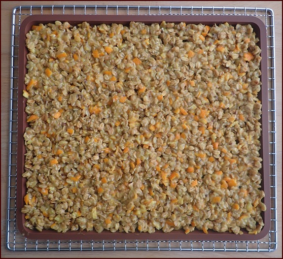 Drying orange granola clusters on a silicone tray.